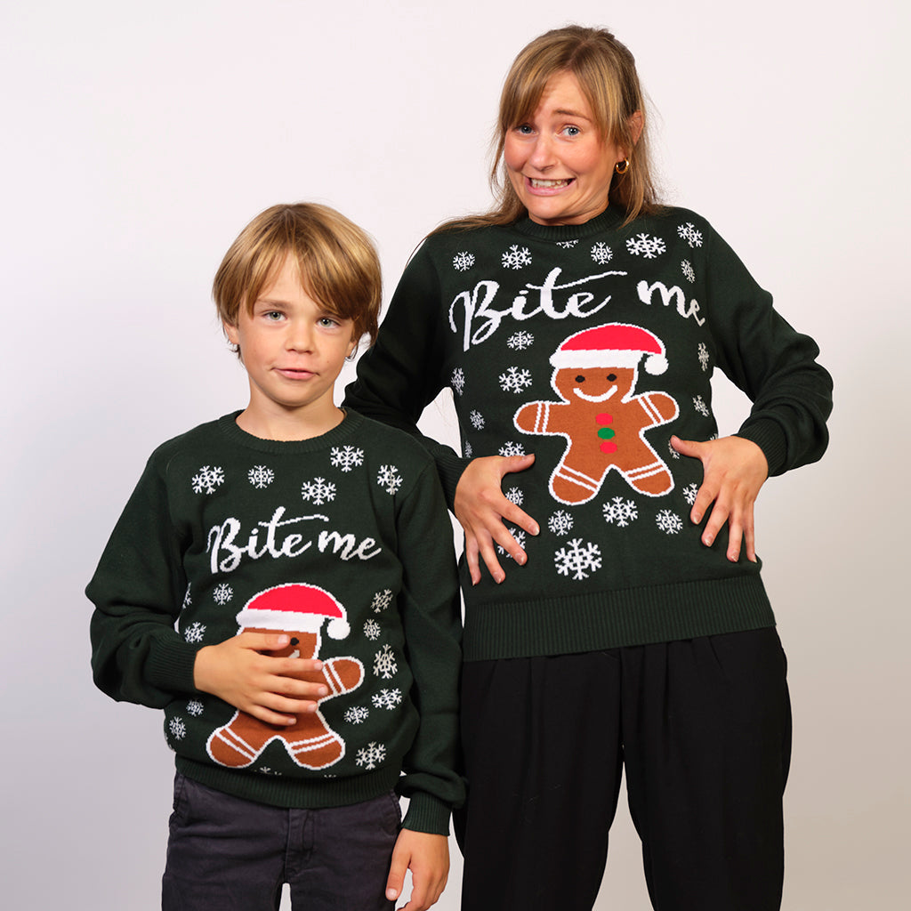 Ein Kind und eine Frau, die einen grünen Weihnachtspulli mit Kuchen und Schneeflocken darauf tragen.